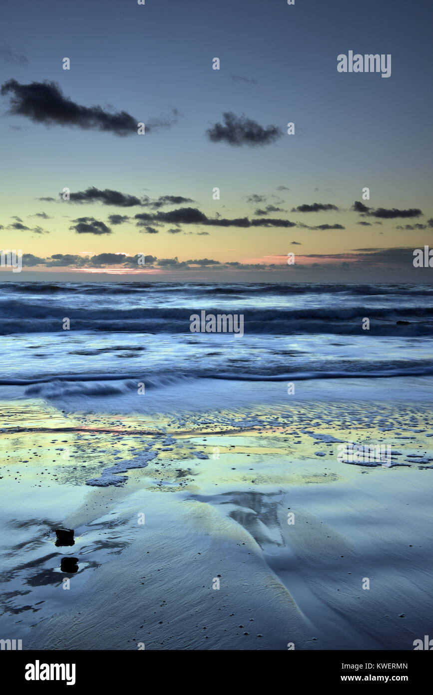 Una bella e atmosferica di scena o seascape con le nuvole specchiata sulla sabbia bagnata sulla spiaggia dalle riflessioni in mare. Bellissima spiaggia tramonto. Foto Stock