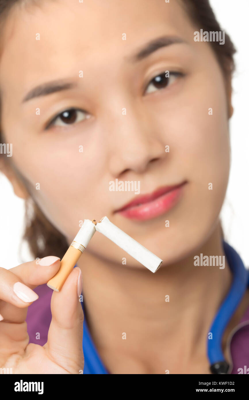 Asian medico o infermiere tenendo la rottura di una sigaretta per illuminare il concetto di smettere di fumare isolato su uno sfondo bianco Foto Stock