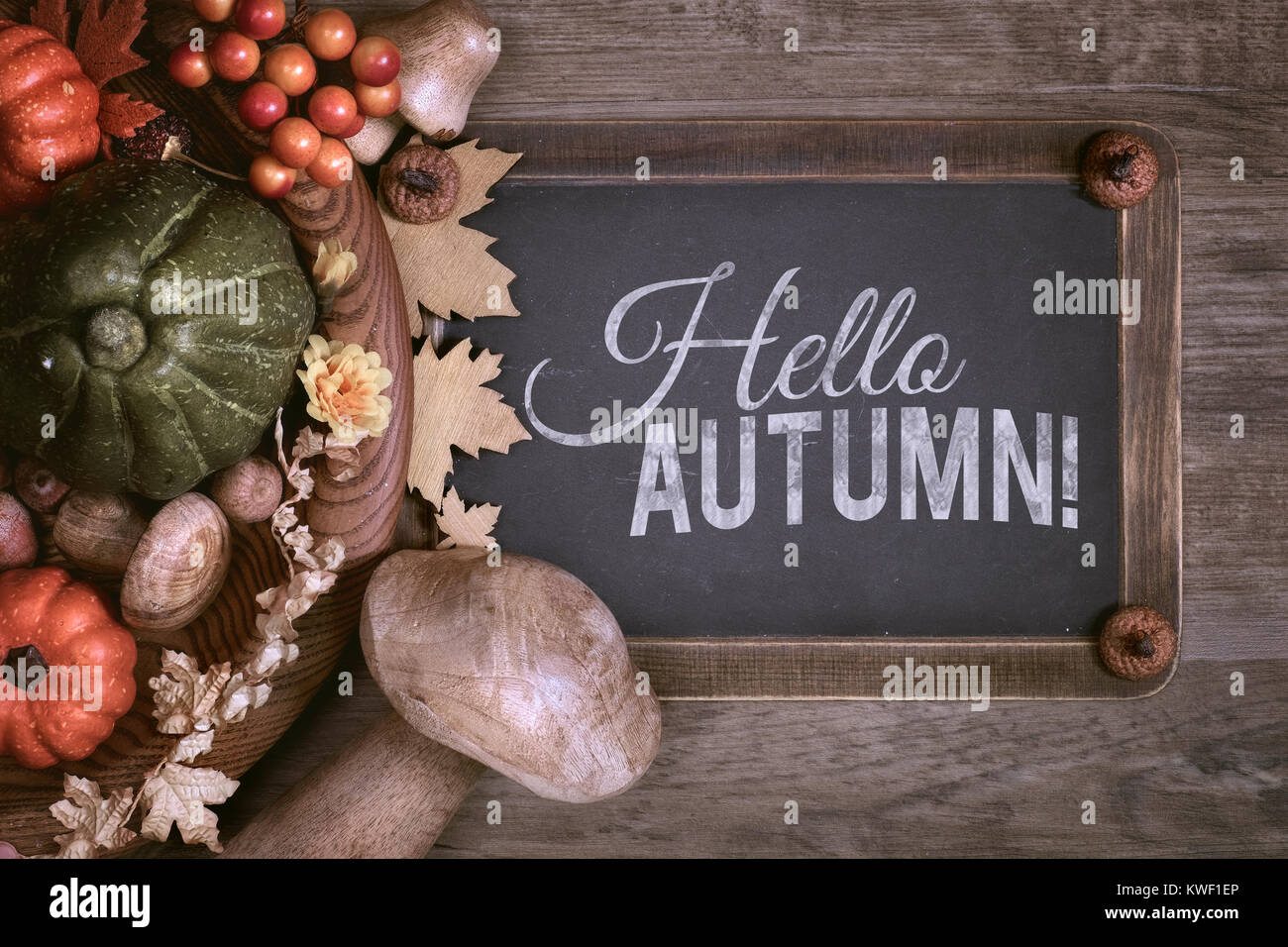 Lavagna con il testo "Ciao autunno"con l'autunno di decorazioni su legno. Vista superiore, tonica immagine. Foto Stock