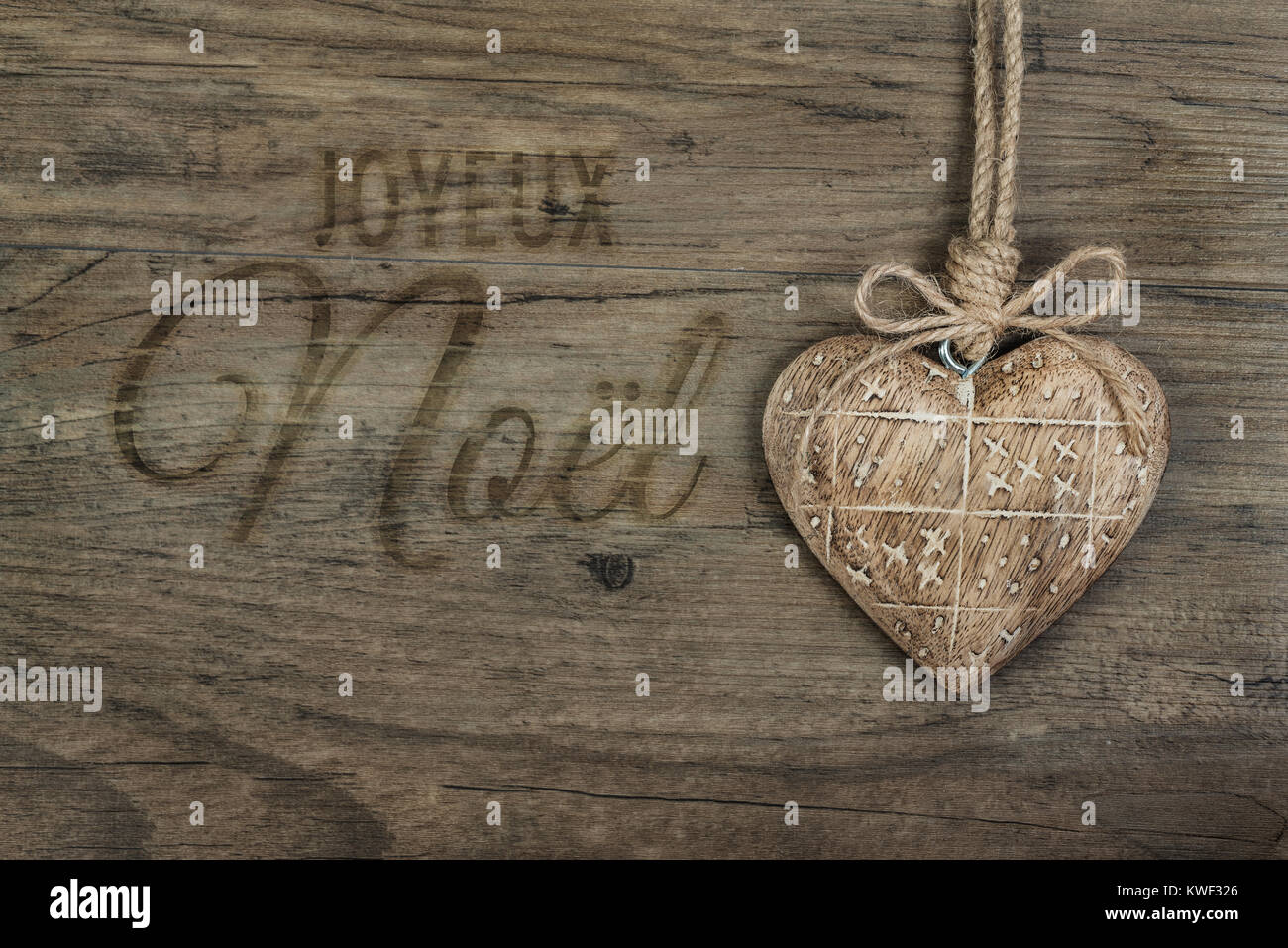 Cuore di legno decorazione su antichi sullo sfondo di quercia e didascalia in francese "Joyeux Noel' in bruciato lettera script Foto Stock