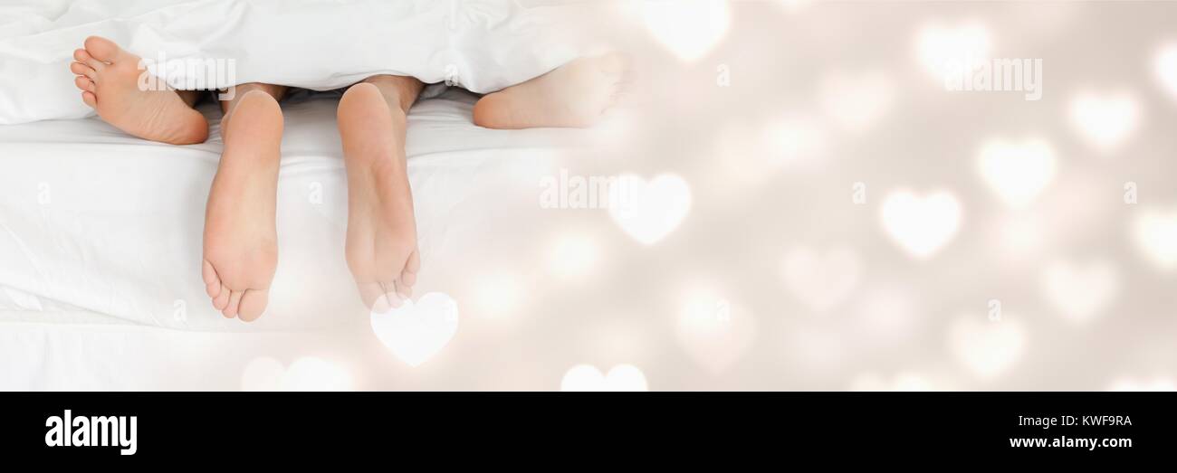 I piedi della coppia nel letto con i cuori di transizione di amore di San Valentino Foto Stock