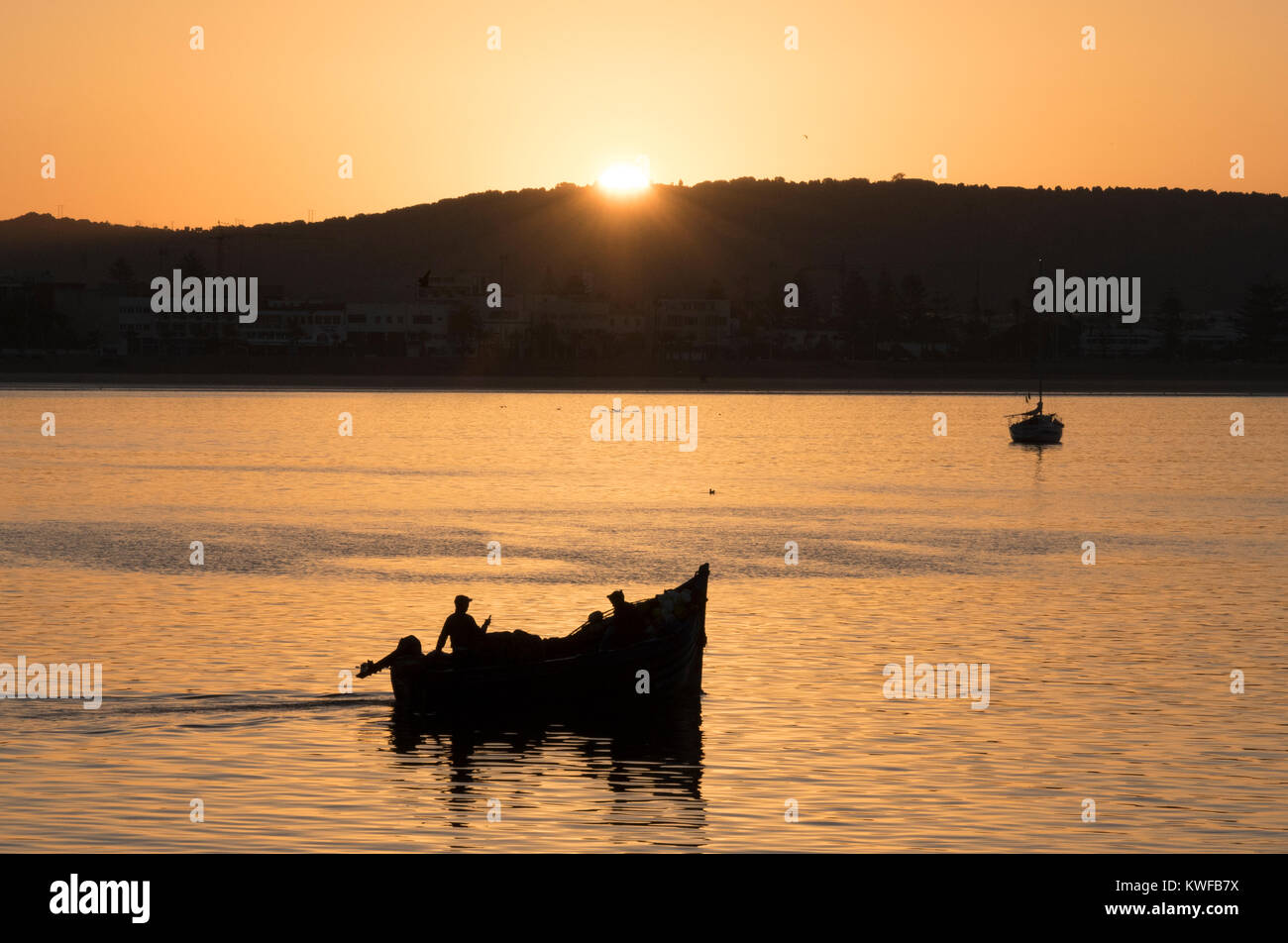 Alba si rompe come piccola pesca costiera barca lascia il porto di Essaouira Costa Atlantica del Marocco. Foto Stock