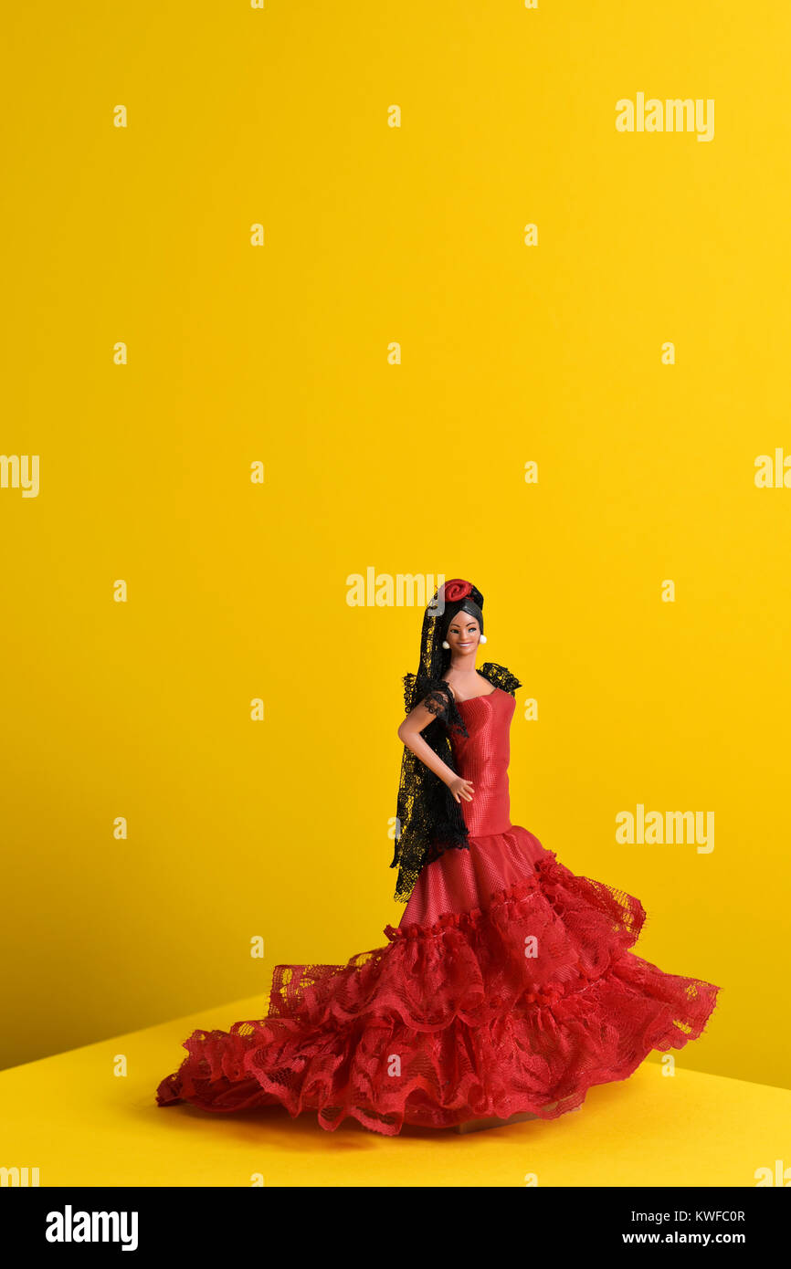 Un tipico spagnolo doll vestita come una ballerina di flamenco, con la caratteristica traje de flamenca, il tipico dot-abito modellato in un giallo backgroun Foto Stock