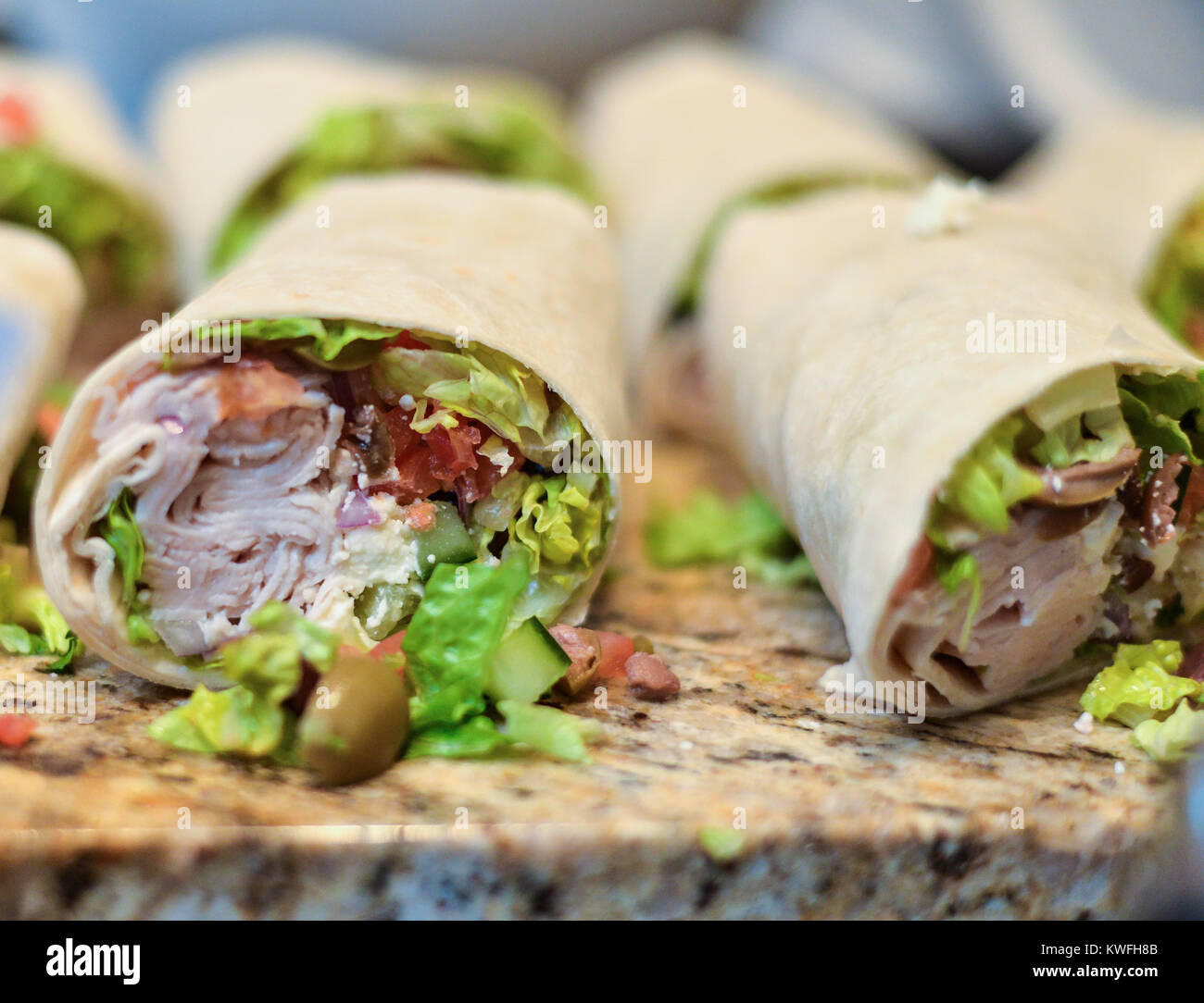 Yummy turchia wrap, tortilla intorno a una sana la verdura e la carne tagliata a metà su un banco in granito Foto Stock