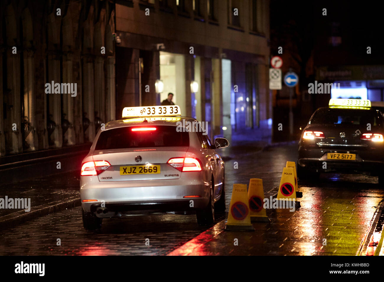 Taxi Parcheggiato fuori pub sulla strada a un umido e ventoso notte a Belfast Irlanda del Nord Regno Unito Foto Stock