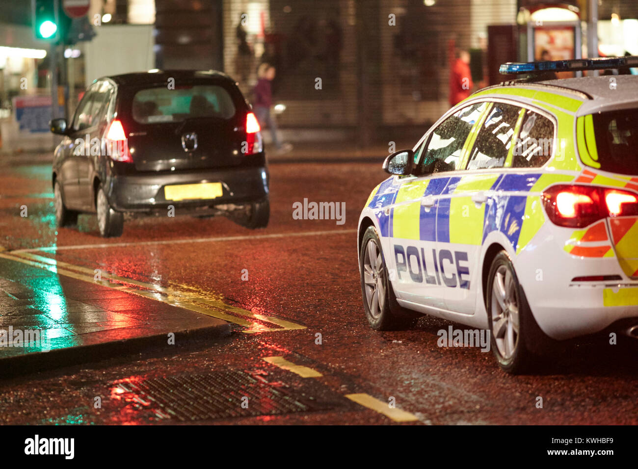 Veicolo polizia seguenti auto a notte nel centro città di Belfast Irlanda del Nord Regno Unito Foto Stock