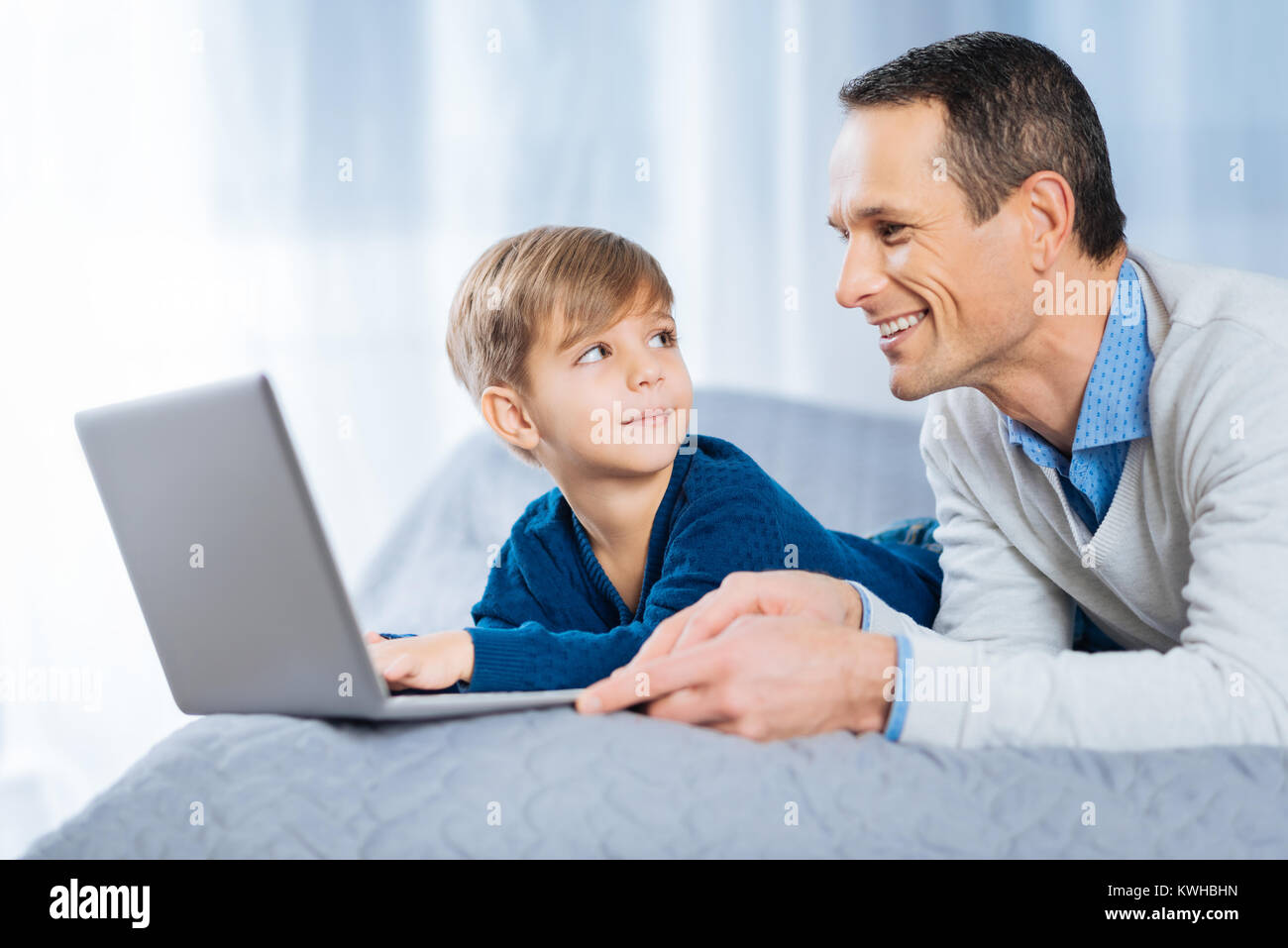 Allegro uomo guarda il suo piccolo figlio di studiare online Foto Stock
