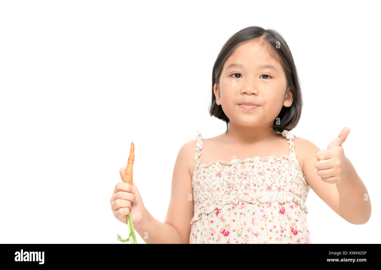 Carino ragazza asiatica come e pollice in su baby carota isolati su sfondo bianco, questo vegetale è una eccezionalmente ricca fonte di caroteni e vitamina A Foto Stock