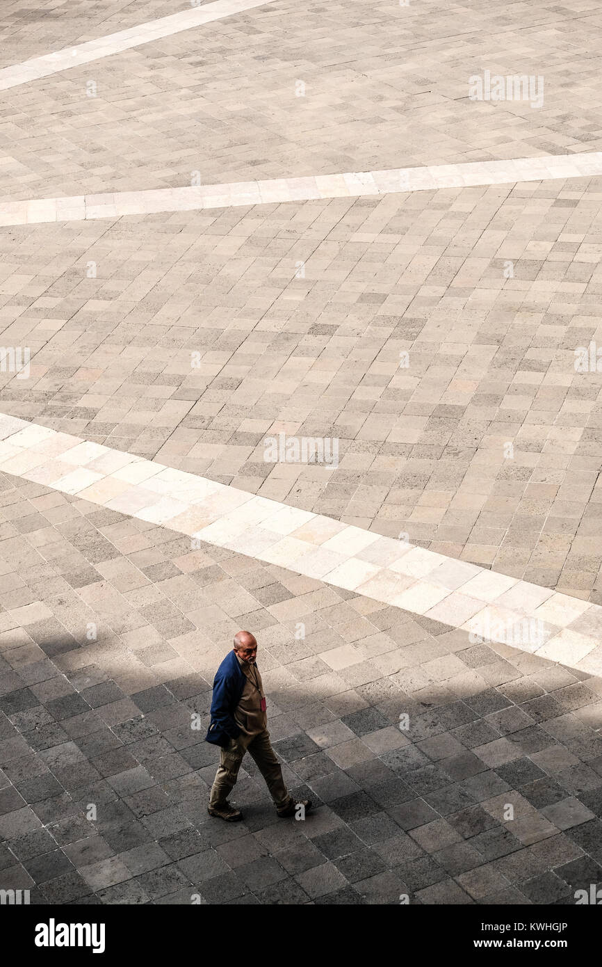 Un uomo solitario a piedi su un quadrato vuoto Foto Stock