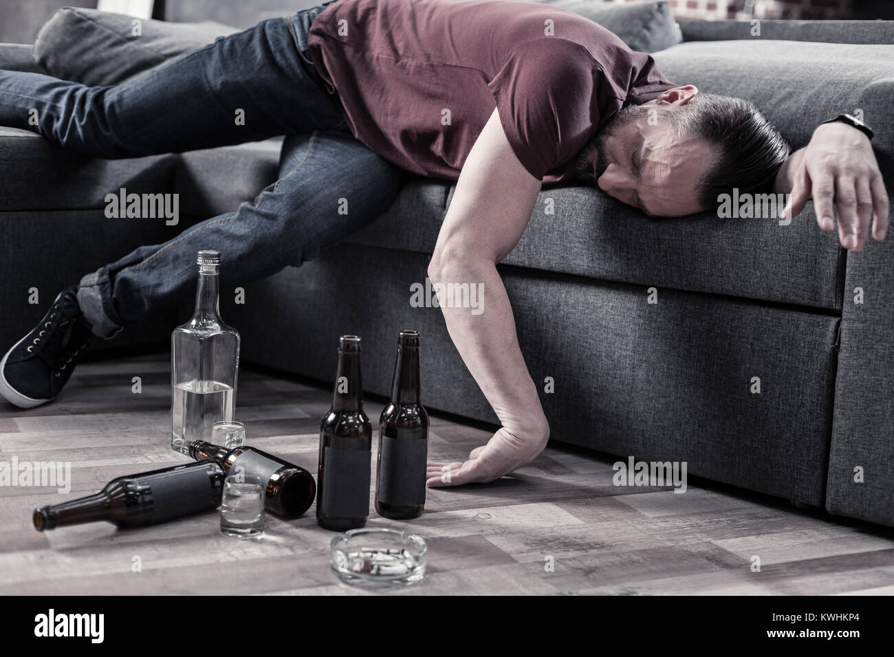 Ubriaco uomo barbuto in appoggio sul divano Foto Stock