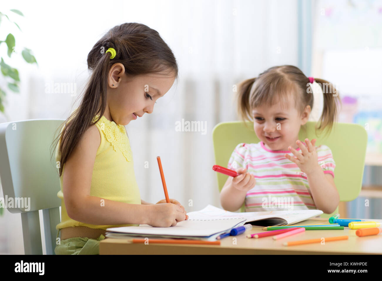 Dei bambini felici disegno nella nursery room Foto Stock