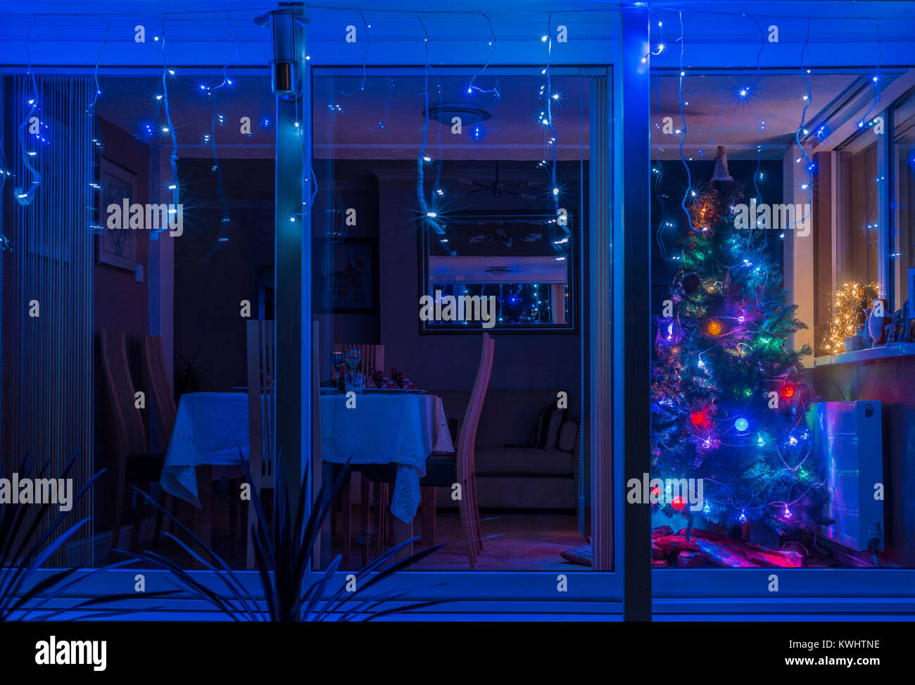 Vista esterna del soggiorno con albero di Natale e tavolo da pranzo stabilite per il menù della vigilia di Natale. Foto Stock