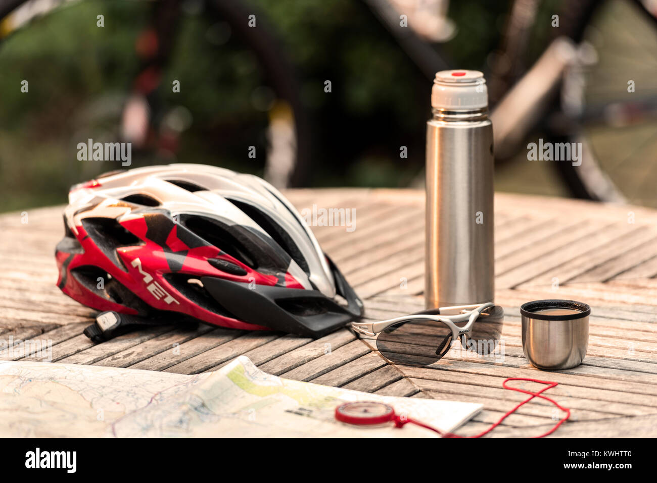Ciclismo casco e bicchieri sul tavolo con pallone di caffè e la mappa. Foto Stock