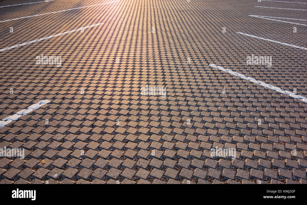 Moderno parcheggio spazi pavimentati con ciottoli quadrati nel tardo pomeriggio la luce del sole. Foto Stock