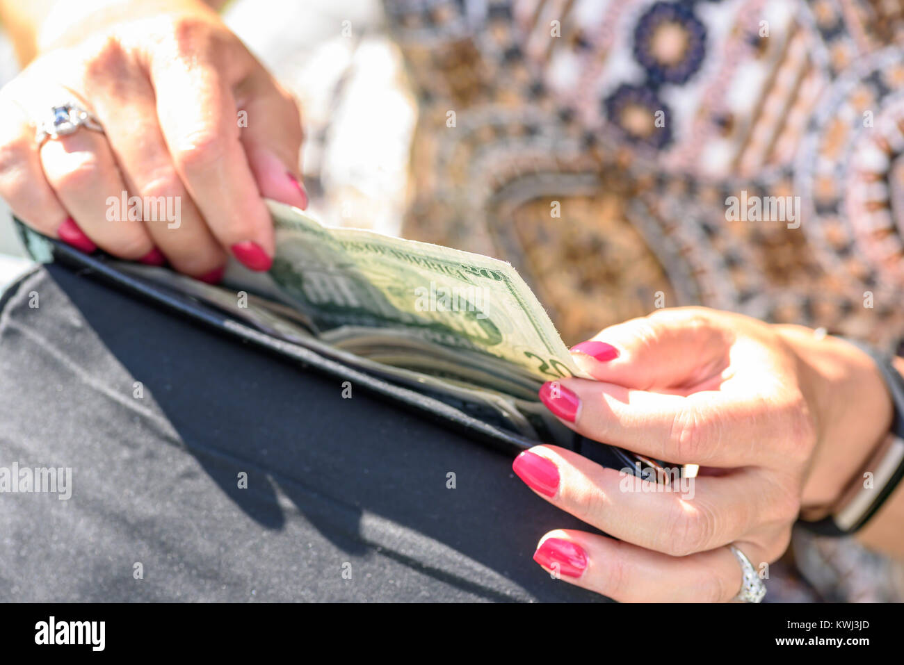 La donna al di fuori alla luce del sole il prelievo di denaro al di fuori del portafoglio nero Foto Stock
