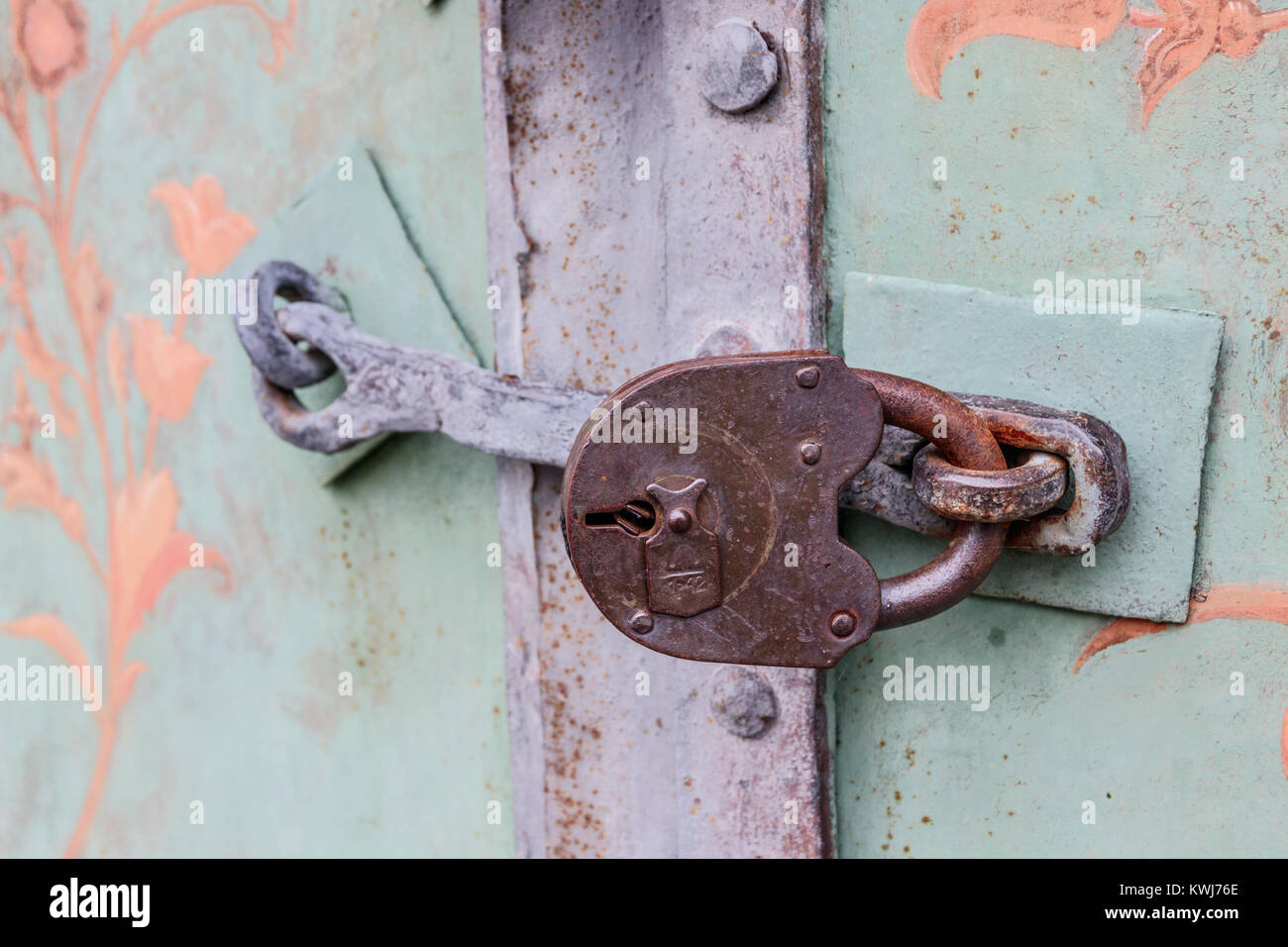 Vecchio, weathered green porta bloccata con barra in metallo e lucchetto arrugginito. Foto Stock