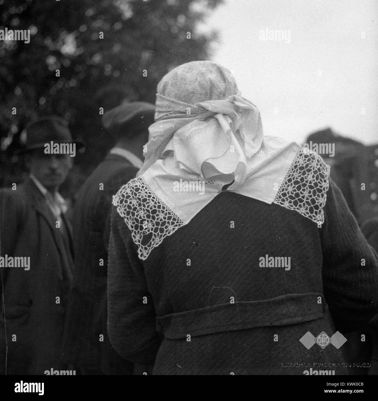 Una fotografia del 1952 cattura una Žumberčanka (donna di Žumberak) che partecipa a una fiera a Šentjernej, indossando un costume regionale in mezzo a un mercato. Foto Stock