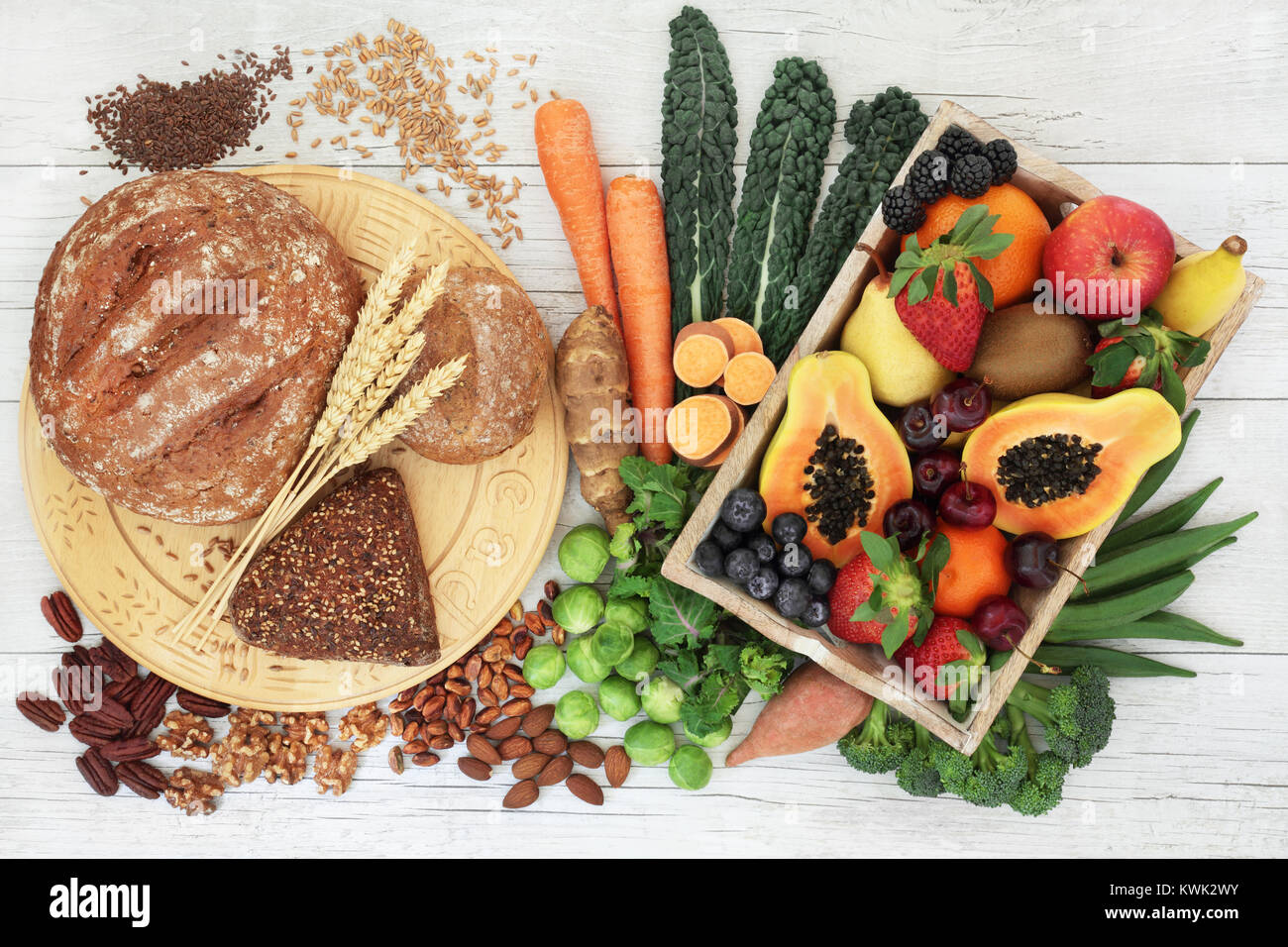 Ad alto contenuto di fibre cibo sano concetto con pane integrale e rotoli, noci, semi, frutta, ortaggi e cereali. Foto Stock