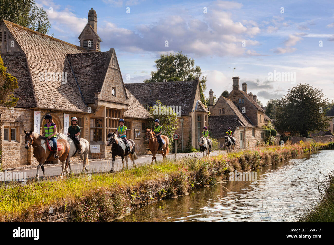Un gruppo di ragazze a cavallo attraverso i Cotswolds village di Lower Slaughter, Gloucestershire, Inghilterra Foto Stock