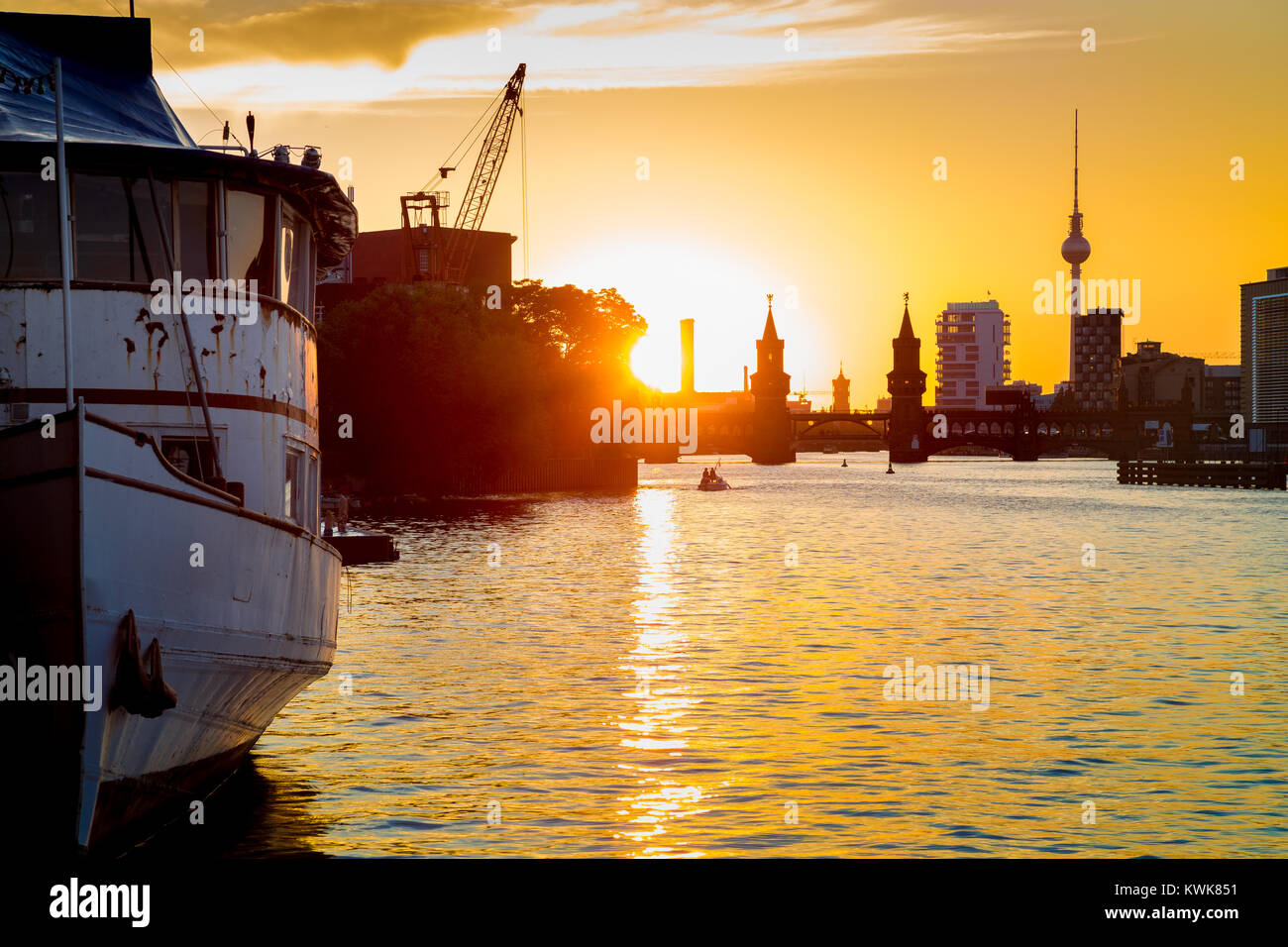 Lo skyline di Berlino con la famosa torre della televisione e il Ponte Oberbaum con la vecchia nave relitto giacente nel fiume Sprea a beautiful Golden luce della sera al tramonto in estate Foto Stock