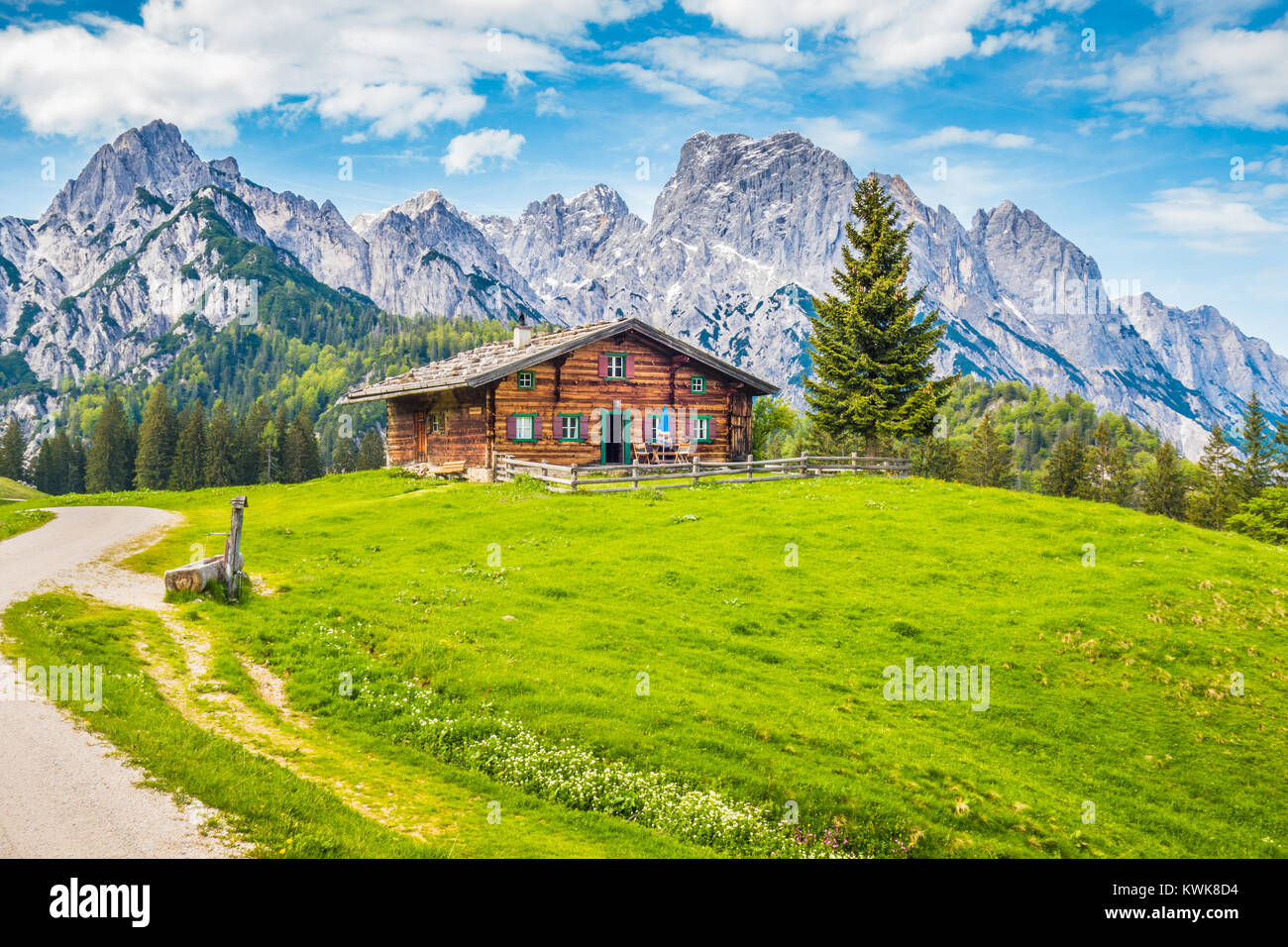 Vista panoramica di idilliaco paesaggio di montagna delle Alpi con chalet di montagna tradizionale e fresco verde pascoli di montagna in primavera Foto Stock