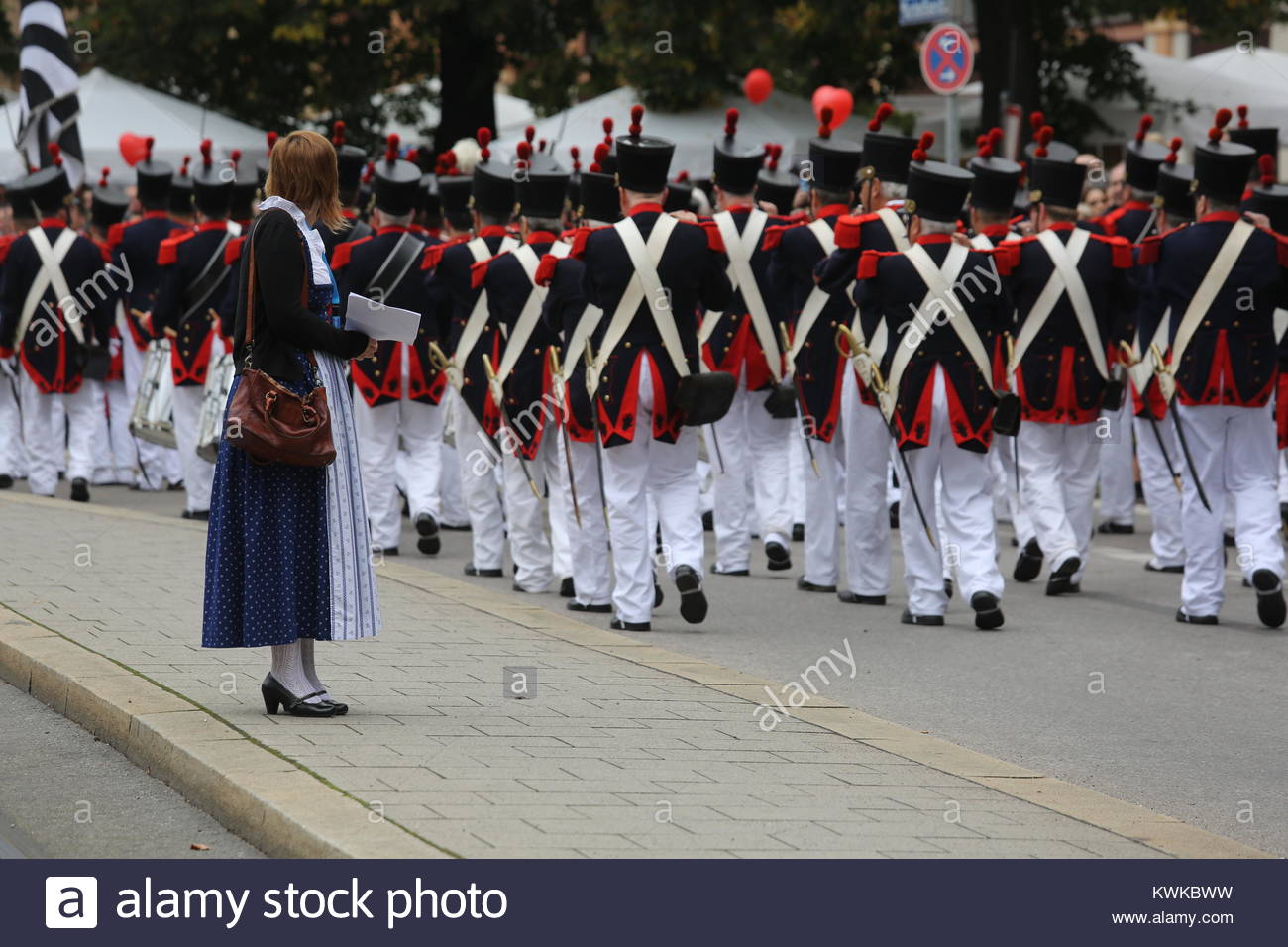 Una donna in abito tradizionale orologi una marching band prendere parte alla parata Oktoberfest a Monaco di Baviera. Foto Stock