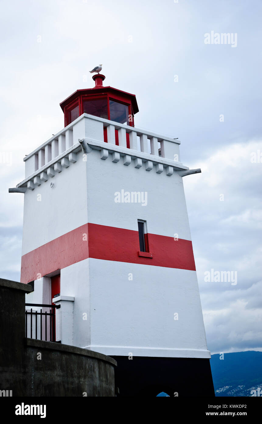 Il bianco e il rosso Brockton Point lighthouse a Stanley Park, con una sea gull appollaiato sulla cima, in Vancouver British Columbia Foto Stock
