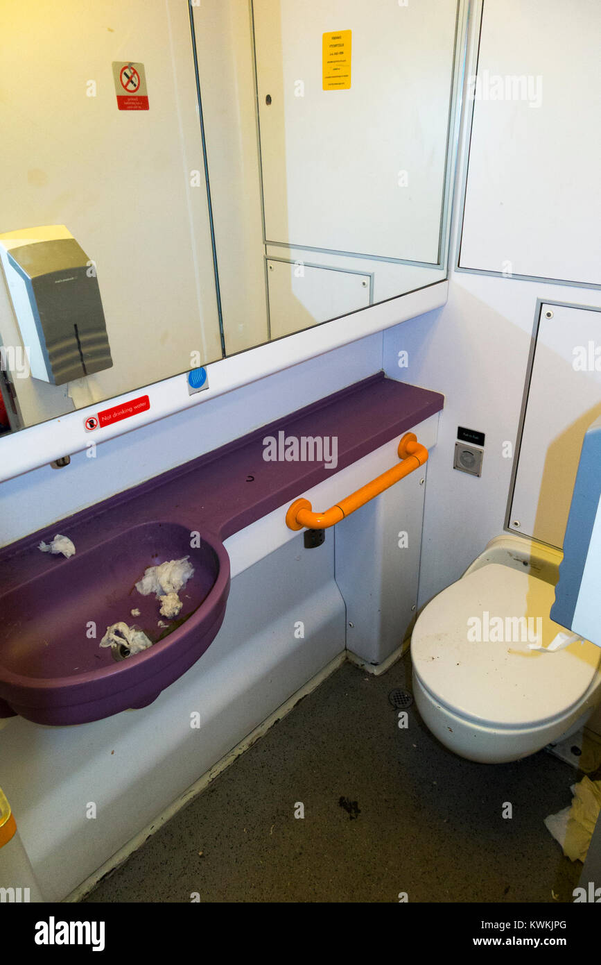 Toilette / WC e lavandini - che viene usato e sporco - attraverso la porta aperta (senza l'accesso a persone disabili) sul treno del Regno Unito nei pressi di Londra SW. Regno Unito. (93) Foto Stock