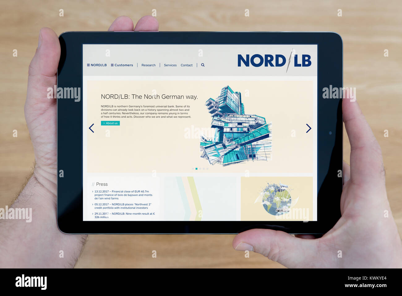 Un uomo guarda al Nord/LB (Norddeutsche Landesbank) Sito web sul suo iPad dispositivo tablet pc, su un tavolo di legno top sfondo (solo uso editoriale) Foto Stock