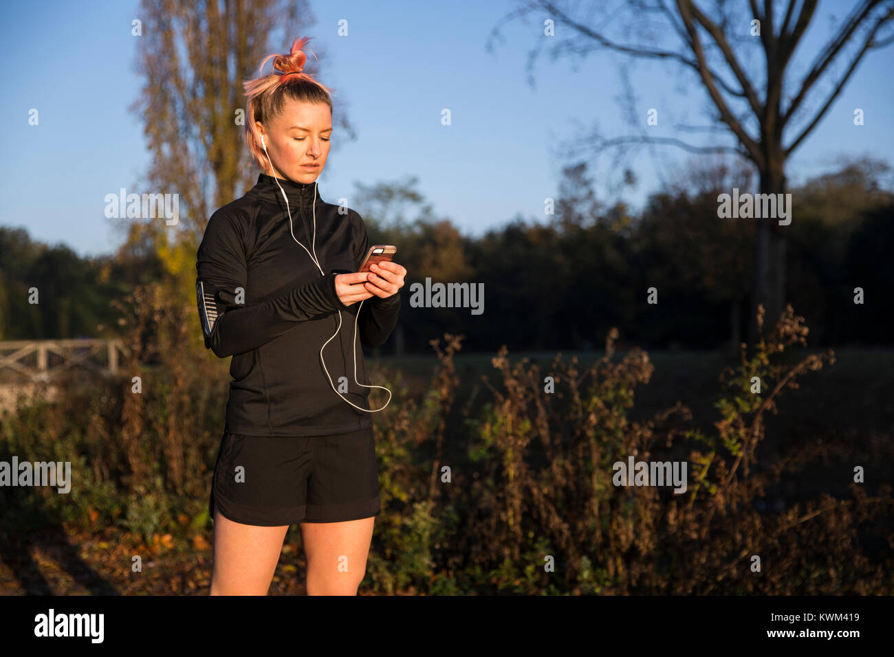 Donna che utilizza smart phone durante l esercizio in posizione di parcheggio Foto Stock