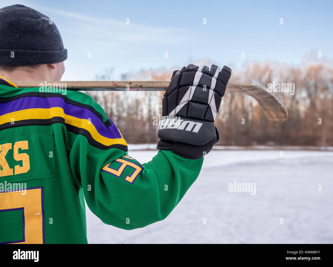 Ragazzo in possesso di una mazza da hockey su un laghetto congelato Foto Stock