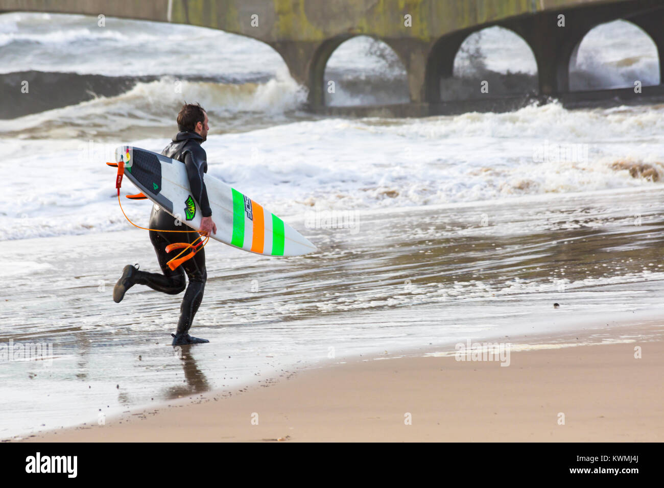 Bournemouth Dorset, England Regno Unito. 4 gennaio, 2018. Regno Unito: meteo surfer tenendo la tavola da surf che corre lungo la spiaggia in una giornata di vento a Bournemouth Beach, come i surfisti a effettuare la maggior parte delle condizioni di vento e grandi onde. Credito: Carolyn Jenkins/Alamy Live News Foto Stock