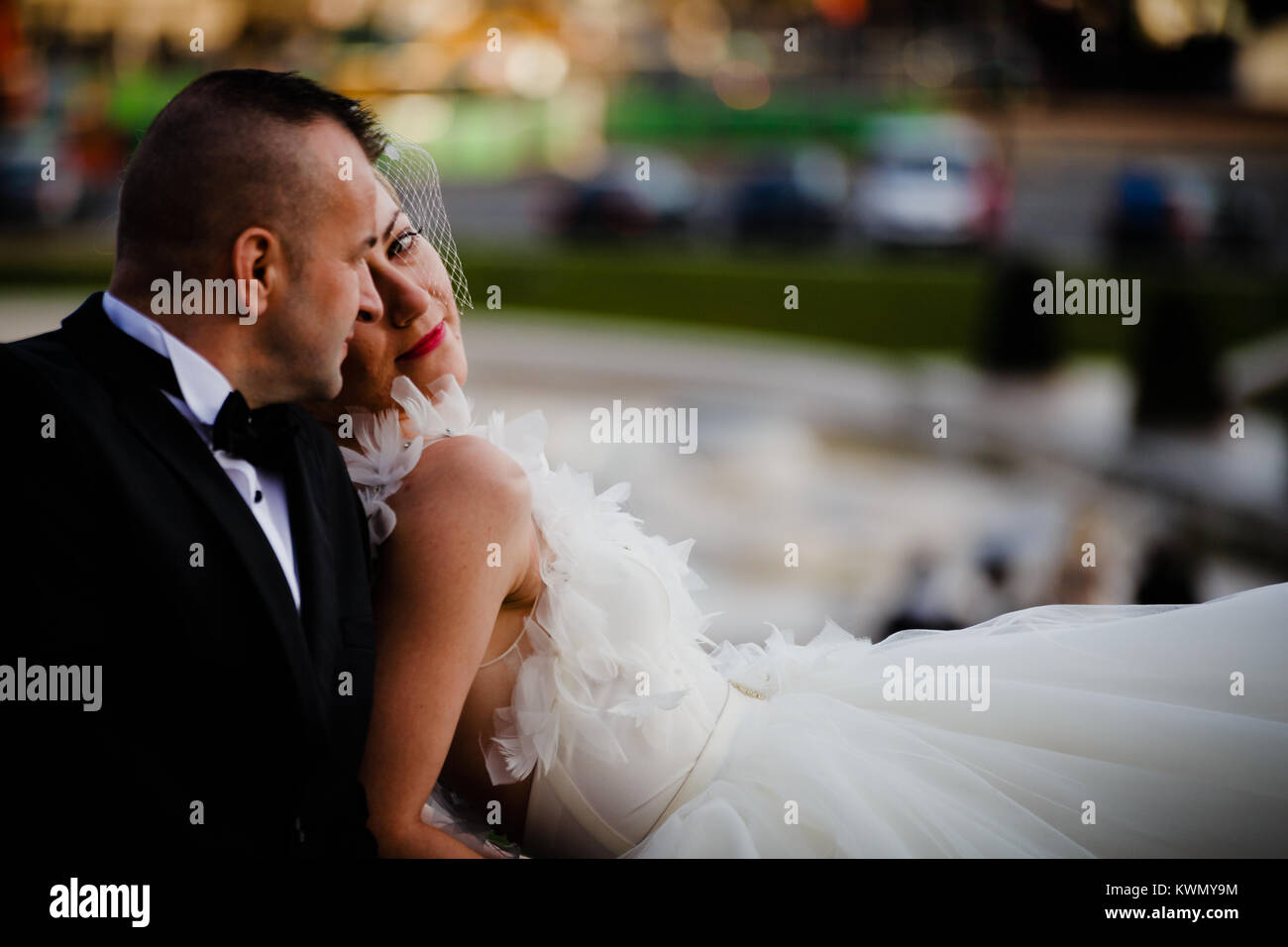 Sposa coppia giovane giacenti e abbracciando all'aperto, sposa indossa abito bianco Foto Stock