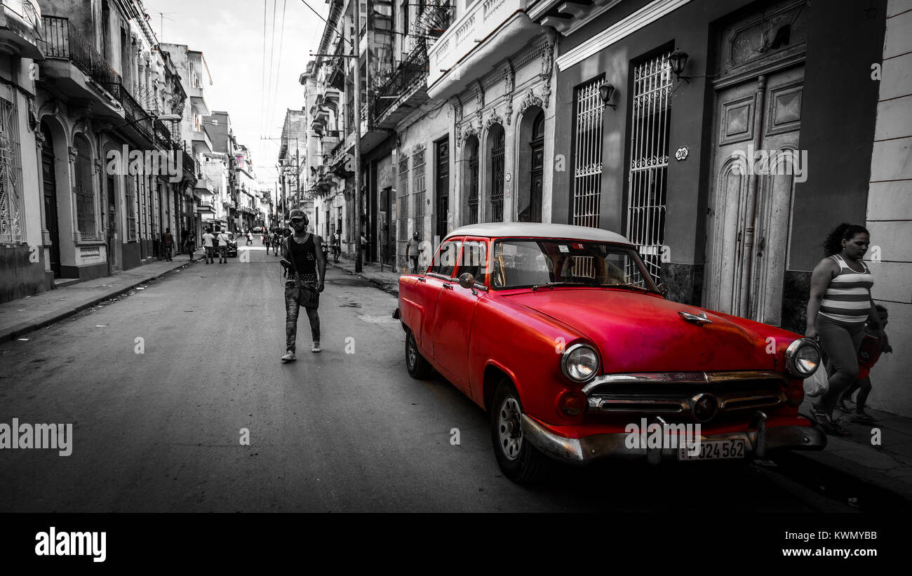 La gente camminare passato rosso vintage automobile parcheggiata su strada Foto Stock