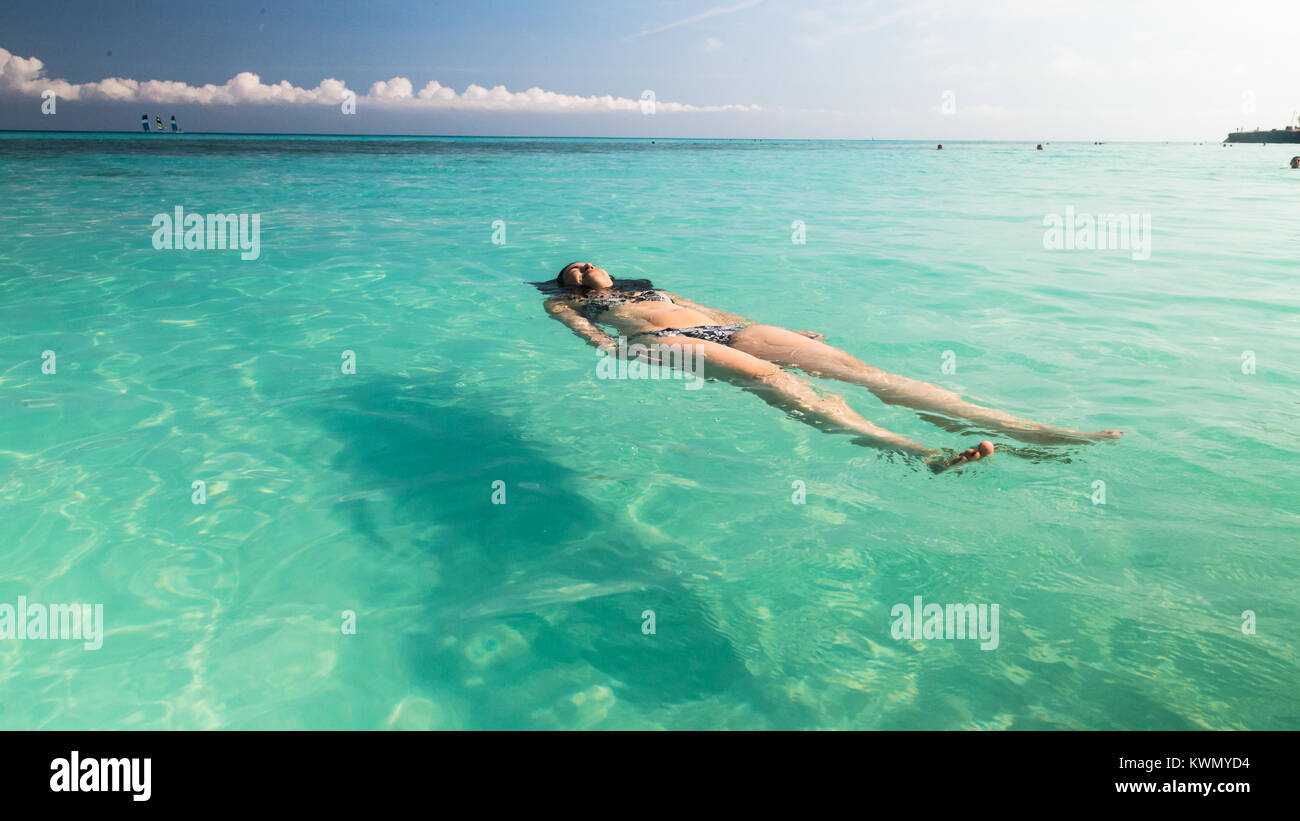Corpo pieno vista della giovane donna galleggiante sul retro in turchese mare tropicale Foto Stock