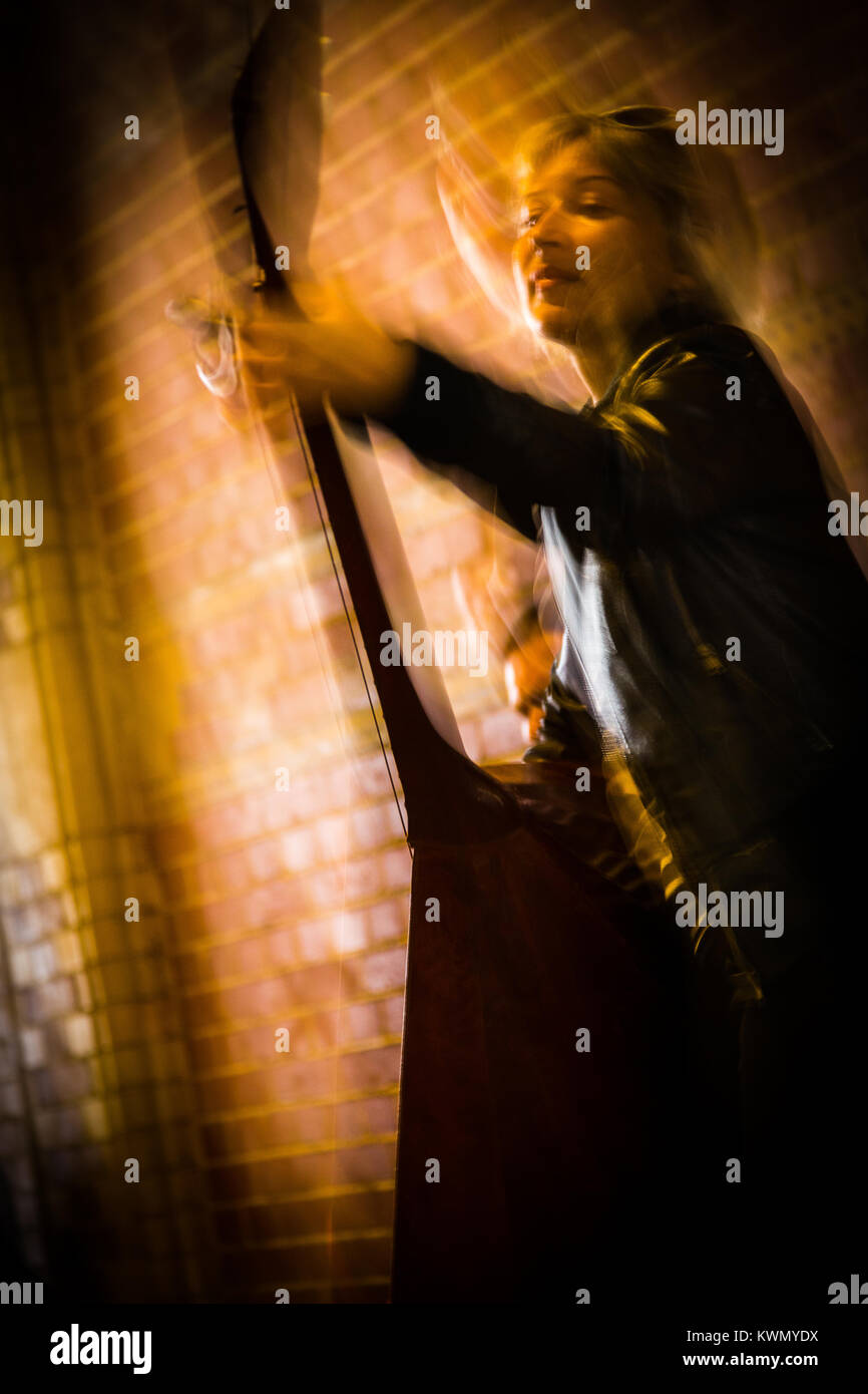 A basso angolo di visione di un ispirato donna riproduzione di un strumento musicale a corda durante una performance dal vivo in luoghi chiusi Foto Stock