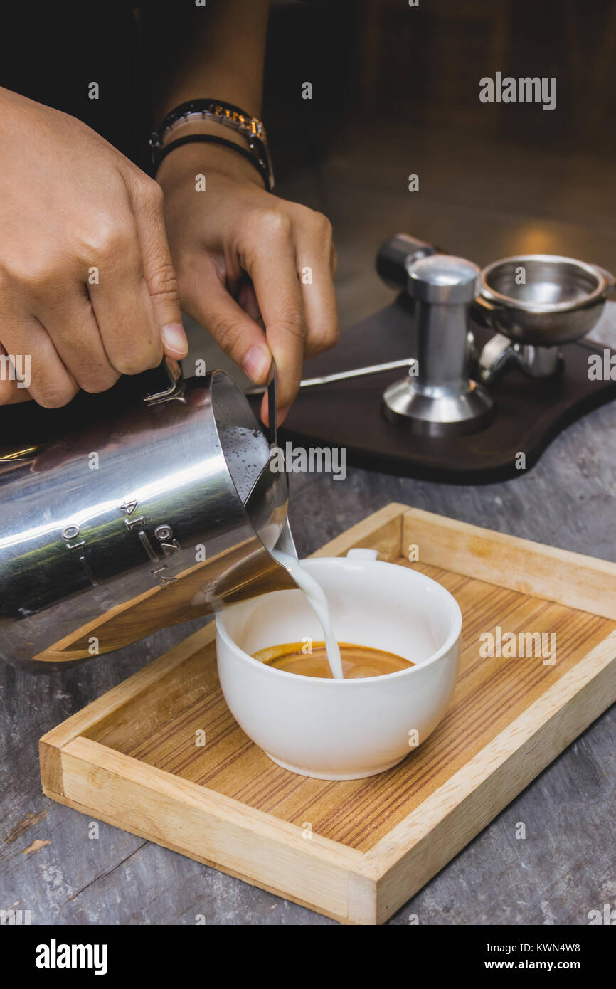 Versare il latte nel caffè , rendendo la tradizione espresso Foto Stock