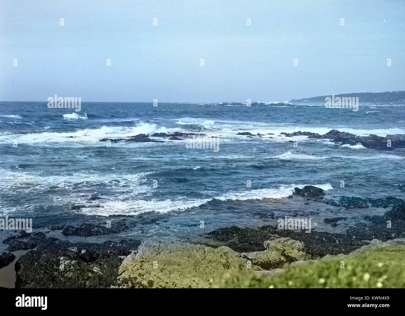 Le onde rompono sulle aspre rocce vulcaniche sul litorale vicino Monterey, California, 1950. Nota: l'immagine è stato colorizzato digitalmente usando un processo moderno. I colori possono non essere periodo-precisa. Foto Stock