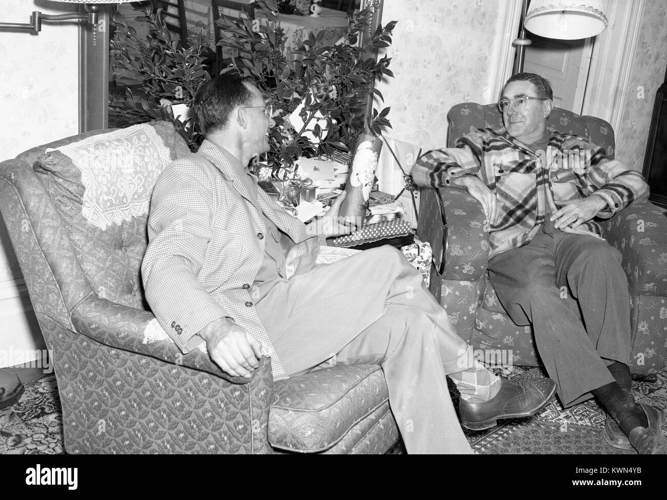 Due amici, sia uomini maturi, sedersi sulle poltrone e conversare, una consegna a un dono per gli altri, Eureka, California, 1950. Foto Stock