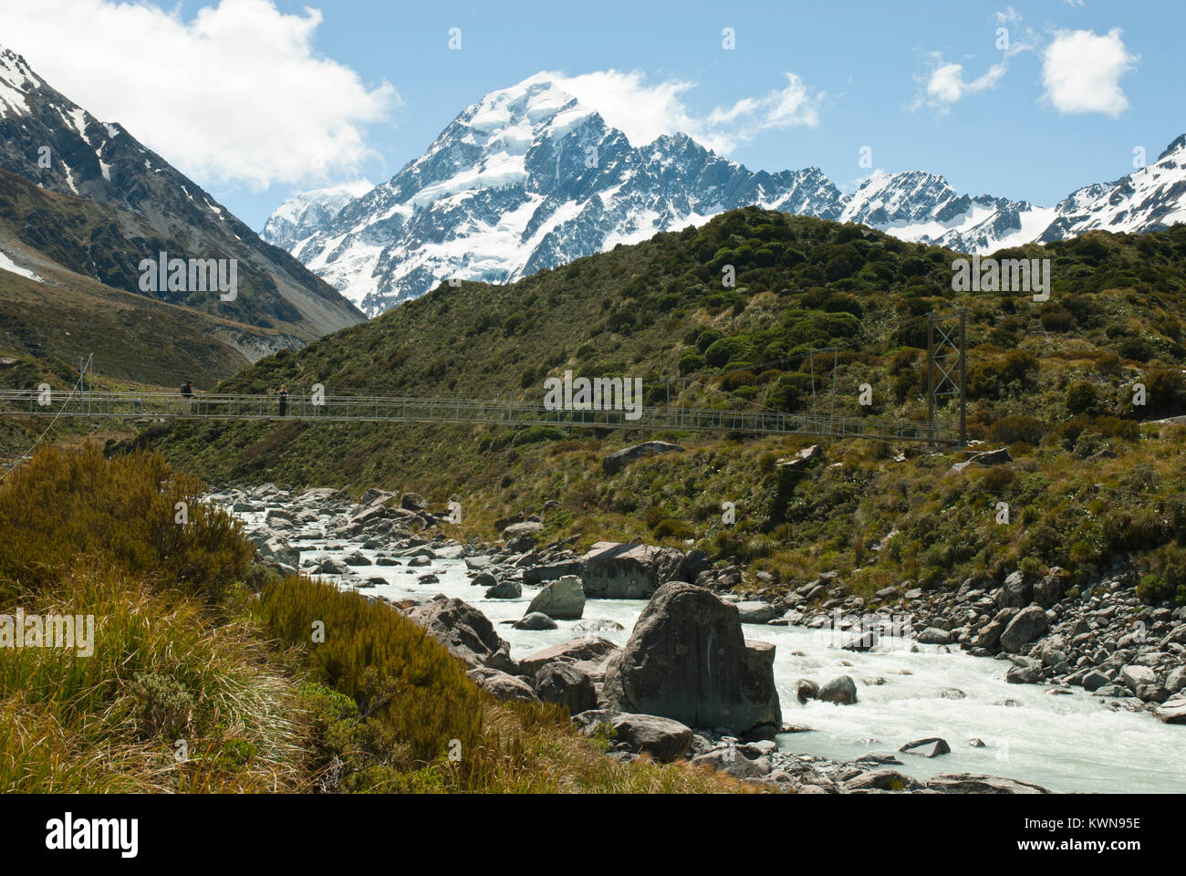 Iconico Mount Cook/Aoraki, Snow capped con Hooker Fiume e ponte di sospensione in primo piano. Soleggiato, cielo blu. Primavera / Estate precoce. Foto Stock