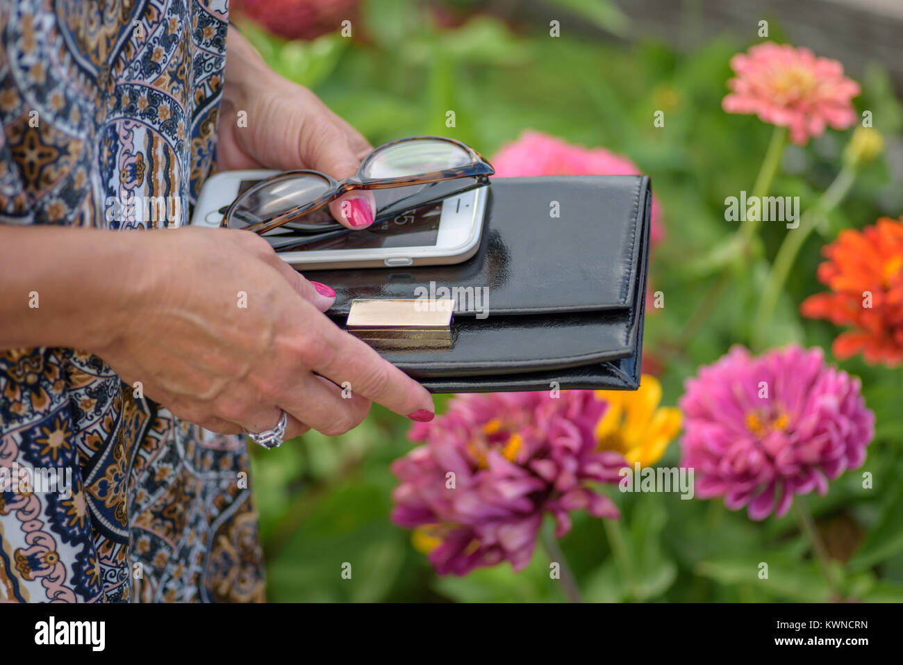 Primo piano della donna azienda wallet, bicchieri e smartphone in Summer Flower Garden Foto Stock