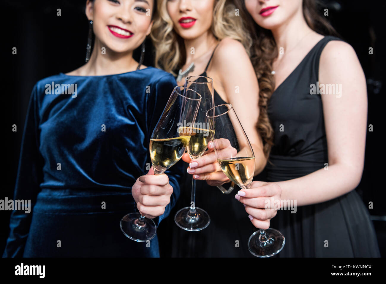 Vista parziale di sorridere le donne in abiti eleganti bicchieri tintinnanti con champagne Foto Stock