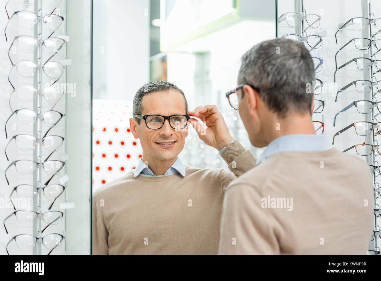 Sorridente uomo caucasico la scelta di un paio di occhiali in ottica Foto Stock
