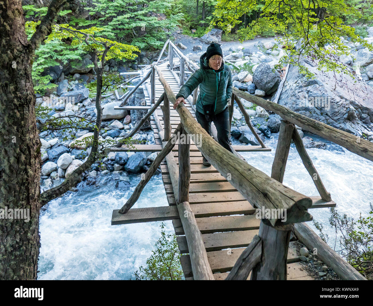 Trekker attraversando una passerella di legno in tutta Rio Ascencio; El Chileno camp site; Parco Nazionale Torres del Paine; Cile Foto Stock