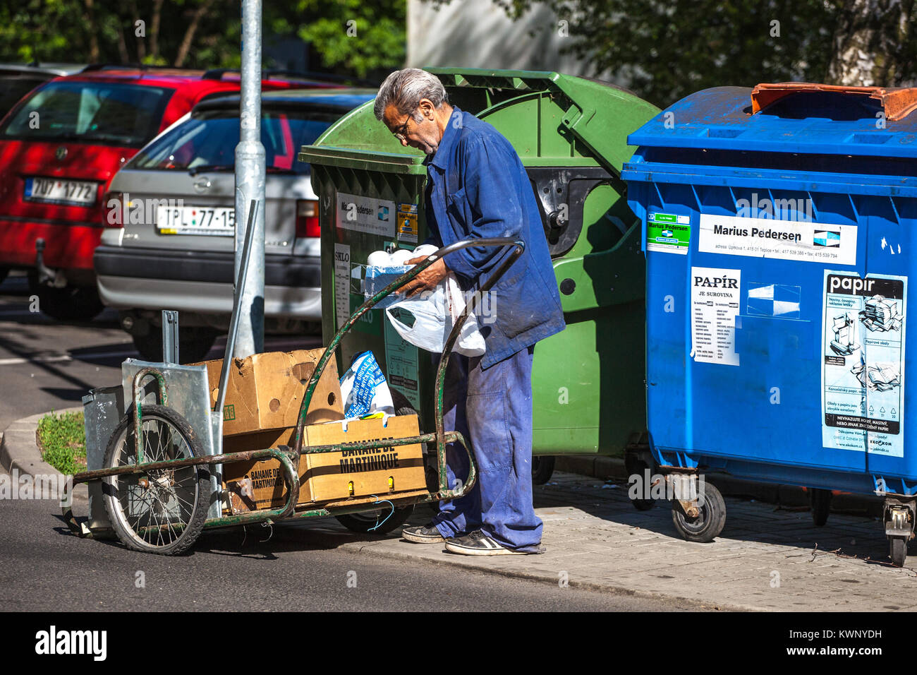 Il povero uomo sta cercando di trovare qualcosa nel bidone della spazzatura, Un pensionato anziano di povertà Foto Stock