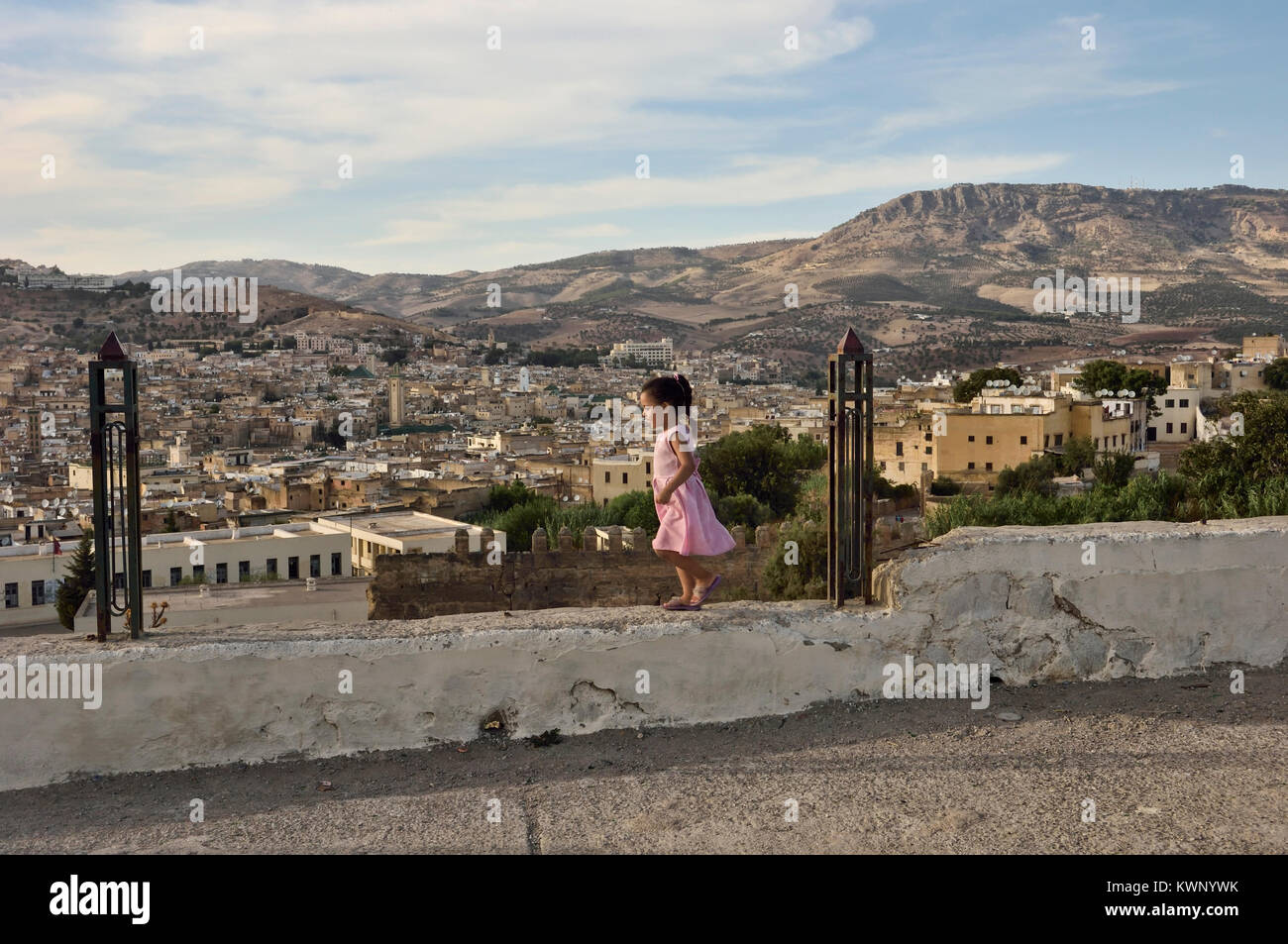 Un bambino che gioca su una parete sopra la città di Fez, Marocco, Africa del Nord Foto Stock