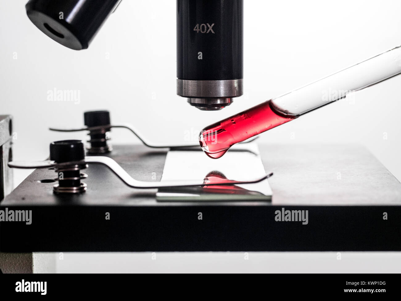 Pipetta contagocce, ponendo un rosso sangue gocciolina di sostanza su un microscopio e vetro per microscopio diapositiva, closeup, sfondo bianco macro retroilluminato Foto Stock
