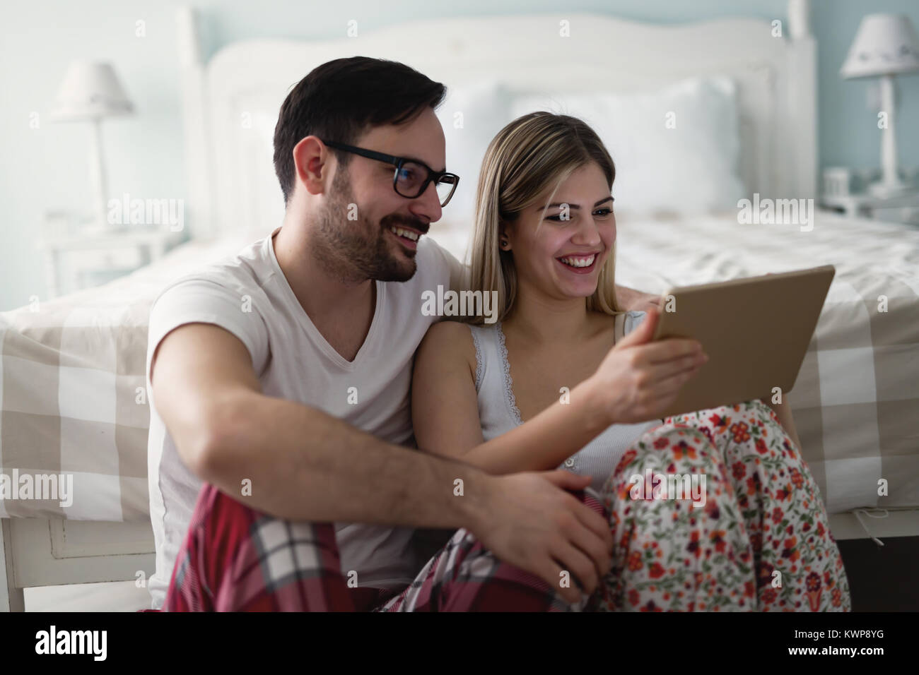 Giovane coppia attraente utilizzando tablet in camera da letto Foto Stock