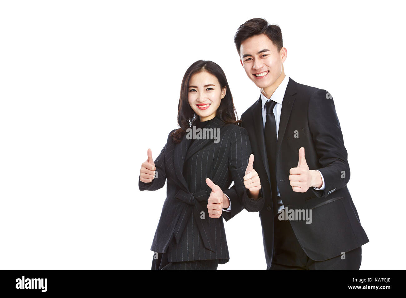 Studio shot di due giovani asiatici corporate executive, imprenditore e imprenditrice e mostra le due-pollice in alto segno, guardando la telecamera sorridendo, isolato Foto Stock