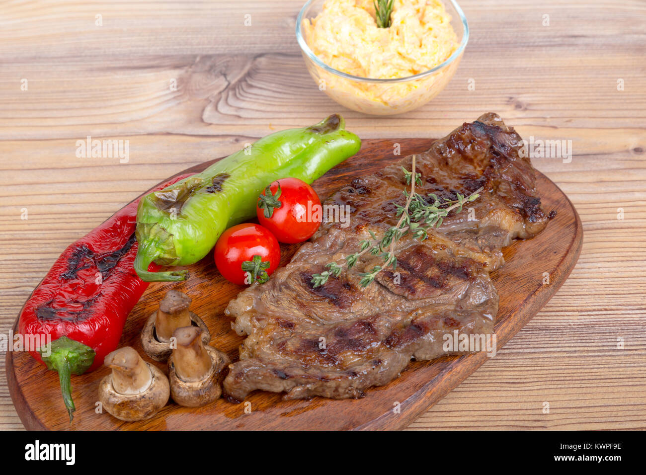 Vista dettagliata di yummy gustosa bistecca alla brace servite sul piatto di legno con di patata e di pomodoro e peperone rosso. Foto Stock